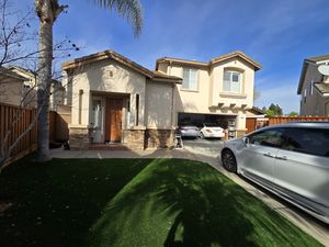 Front View of Two-Story Home with Synthetic Lawn and Open Garage