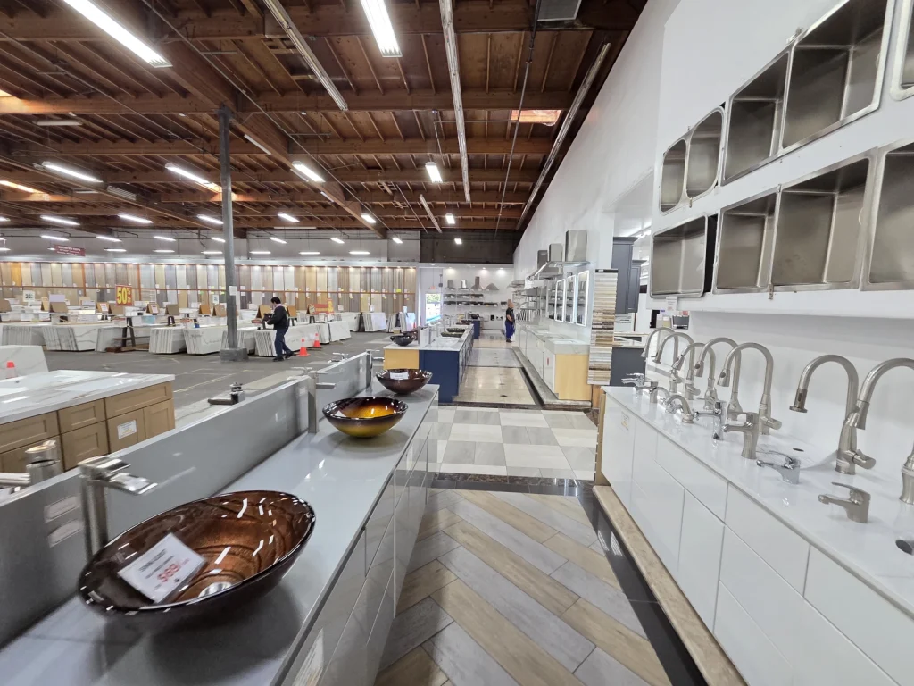 Bathroom vanities at UNI - Marble & Granite, showcasing a variety of sinks, faucets, and countertop displays in a spacious showroom.
