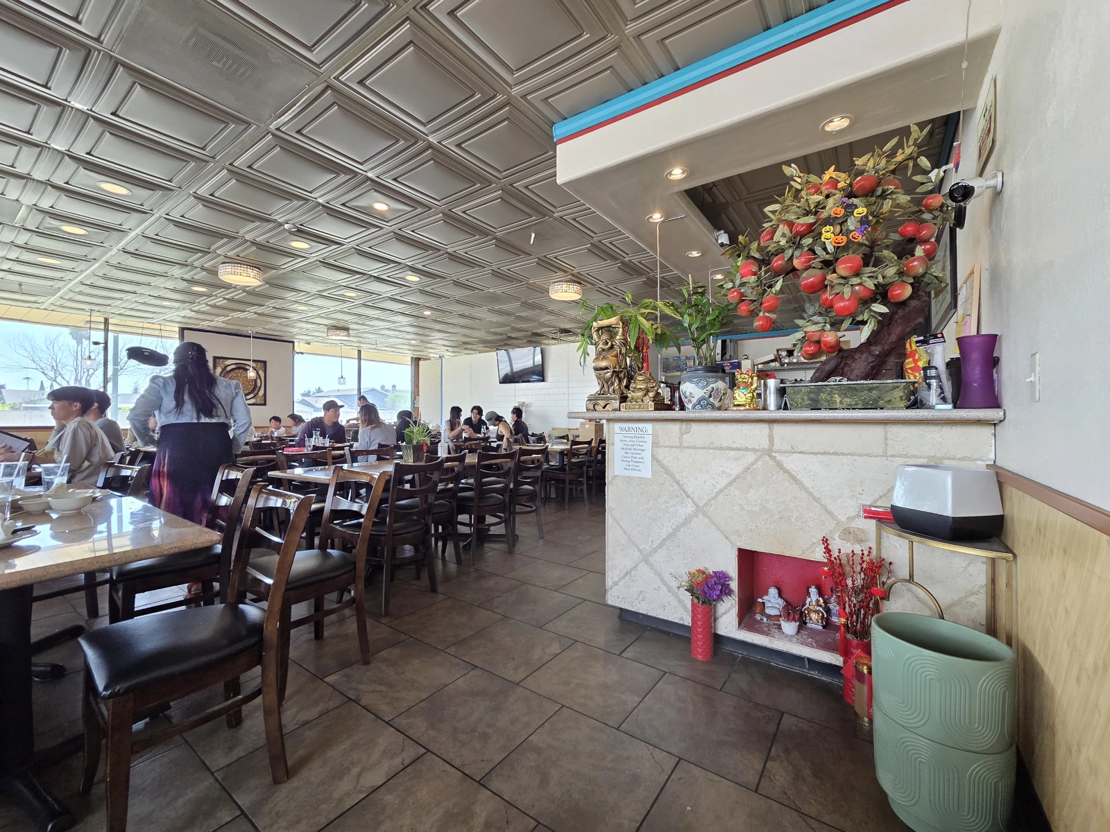 Another angle of the dining area at Com Tam Dat Thanh, showing empty chairs, tables, and a cozy seating arrangement with a well-lit and spacious ambiance.